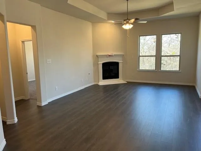 an empty room with wooden floor fireplace and windows