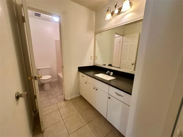 a bathroom with a granite countertop sink a toilet and a mirror