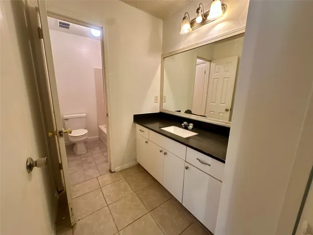 a bathroom with a granite countertop sink a toilet and a mirror