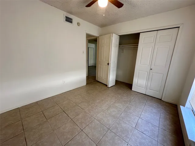 a view of an empty room and a chandelier fan