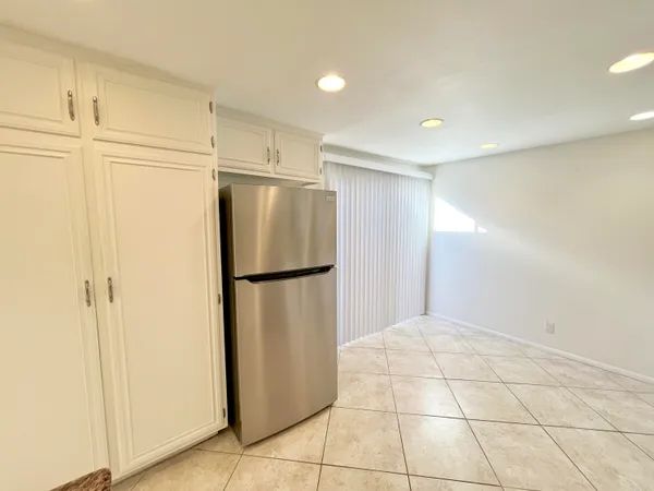 a view of a refrigerator in kitchen and white cabinets