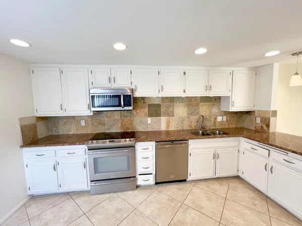 a kitchen with cabinets stainless steel appliances and sink