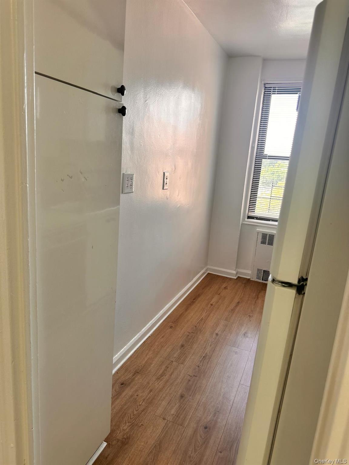 150-11 72nd Road, Unit 6F Queens, NY 11367 - Photo 27 of 31 a view of an empty room with wooden floor and a window