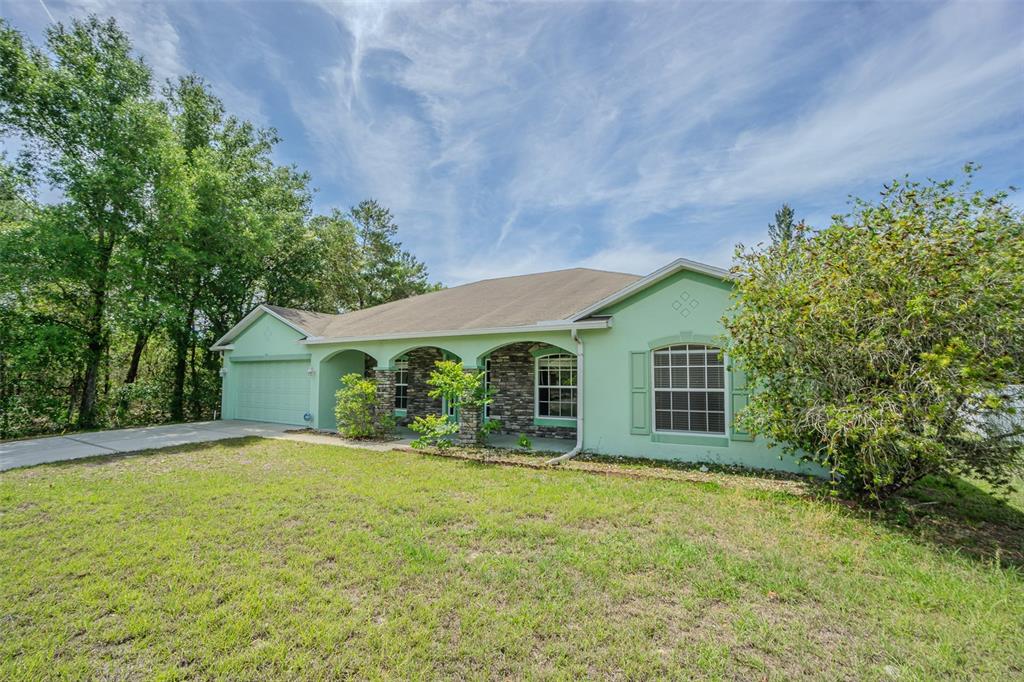 6283 Lorraine Lane Spring Hill, FL 34608 - Photo 3 of 27 front view of house with yard and trees in the background
