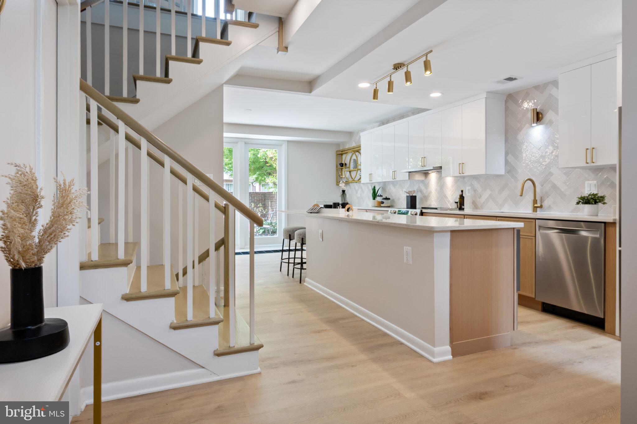 1309 4th Street Southwest, Unit TH9 Washington, DC 20024 - Photo 7 of 63 a kitchen with kitchen island granite countertop a sink and a stove top oven with wooden floor