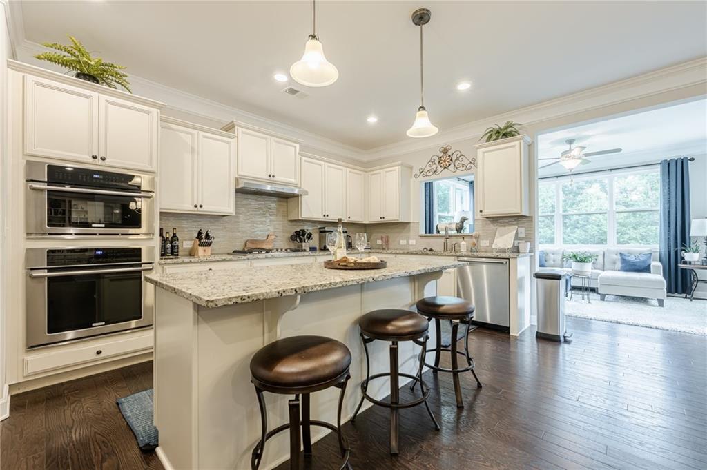 5515 Cheatam Avenue Cumming, GA 30040 - Photo 23 of 99 a kitchen with stainless steel appliances granite countertop a stove a sink a microwave a island with a dining table and chairs