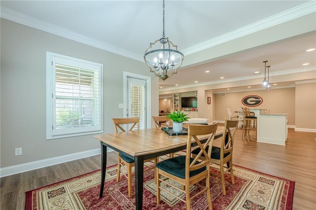 5515 Cheatam Avenue Cumming, GA 30040 - Photo 74 of 99 a dining room with wooden floor a chandelier a wooden table and chairs