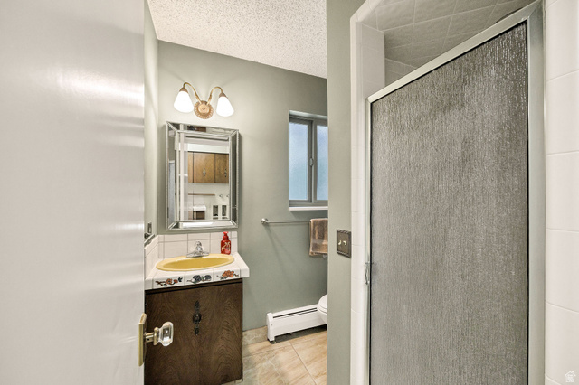 1365 Sumac Drive Logan, UT 84321 - Photo 26 of 66 Bathroom featuring a decorative vanity mirror, a vanity light fixture with two sconces, a wood-finish vanity cabinet, and an enclosed shower with textured glass