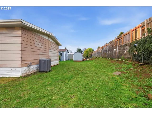 a view of a backyard with plants and large trees