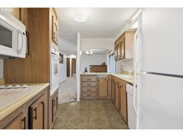 a kitchen that has a lot of white cabinets and stainless steel appliances