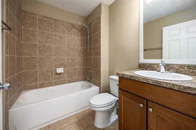 a bathroom with a granite countertop sink a toilet a mirror a bathtub and shower