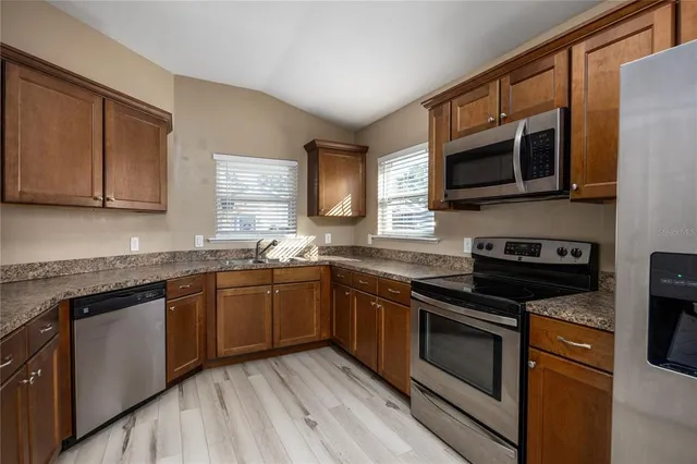 a kitchen with stainless steel appliances granite countertop a stove microwave and sink