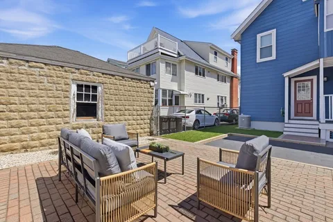 a view of a patio with couches table and chairs with wooden floor and fence
