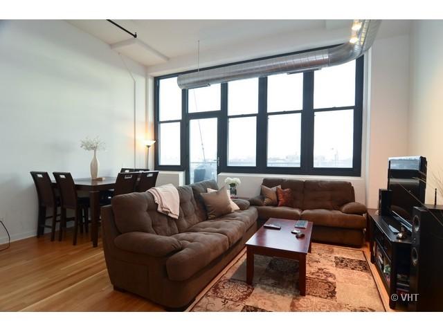 1224 West Van Buren Street, Unit 802 Chicago, IL 60607 - Photo 3 of 10 a living room with furniture a large window and a flat screen tv
