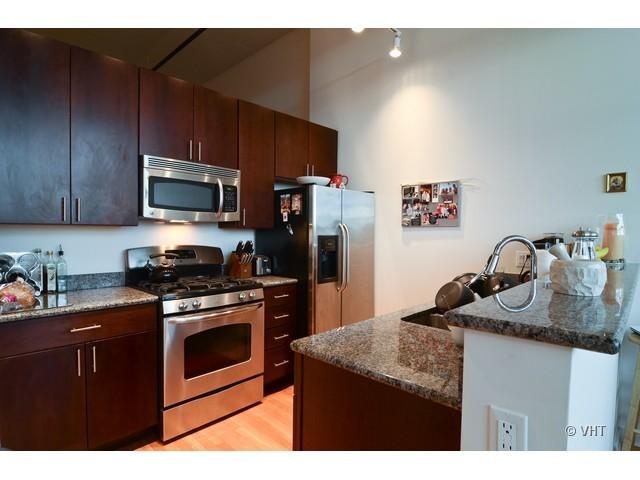 1224 West Van Buren Street, Unit 802 Chicago, IL 60607 - Photo 4 of 10 a kitchen with stainless steel appliances granite countertop a sink stove microwave and refrigerator