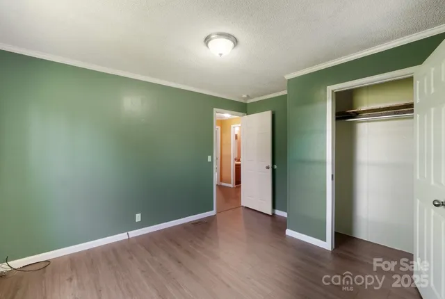 a view of an empty room with wooden floor and closet