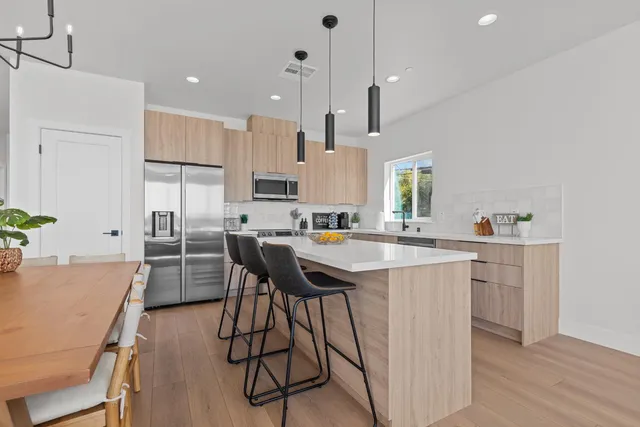 a kitchen with stainless steel appliances kitchen island a table chairs sink and cabinets