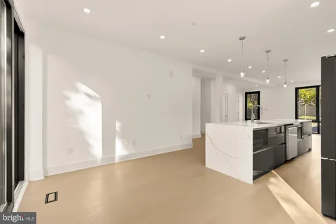 a large kitchen with stainless steel appliances a large counter top a refrigerator and a more window