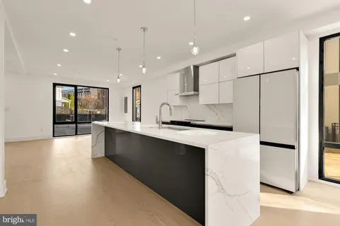 a large kitchen with stainless steel appliances a large counter top a refrigerator a stove a sink a oven and a refrigerator