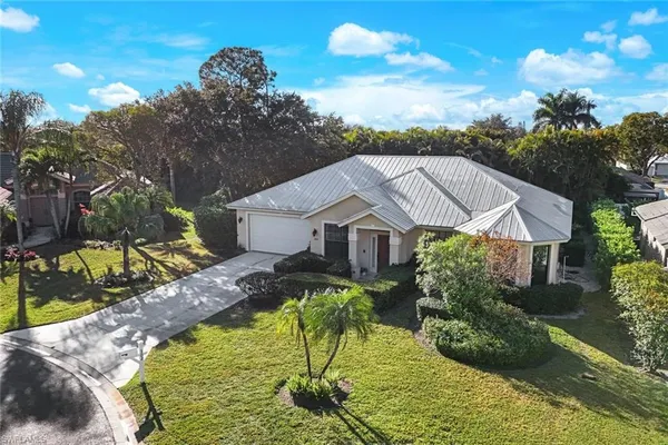 a view of a house with a big yard plants and large tree