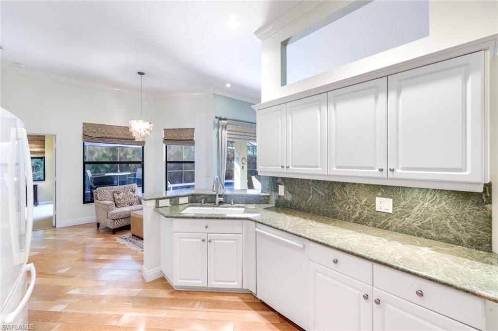 302 Sawgrass Court Naples, FL 34110 - Photo 12 of 40 a kitchen with granite countertop a sink and white cabinets