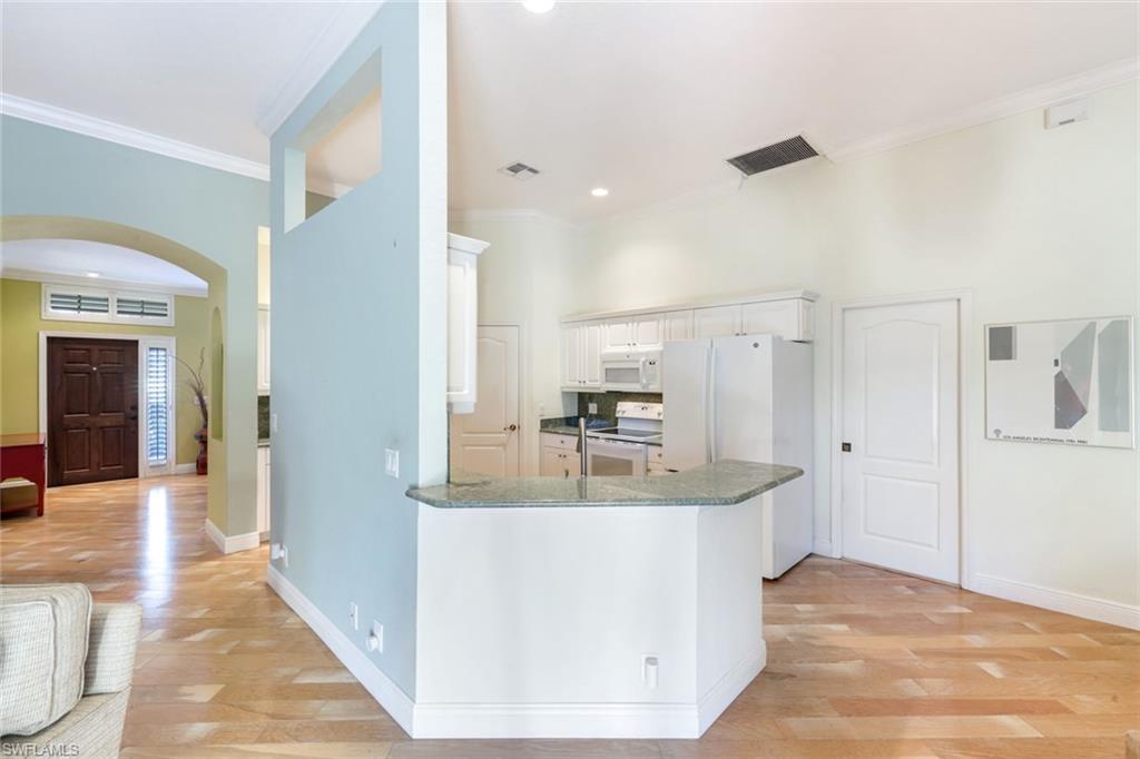 302 Sawgrass Court Naples, FL 34110 - Photo 13 of 40 a view of a kitchen with kitchen island a sink wooden floor and a living room view