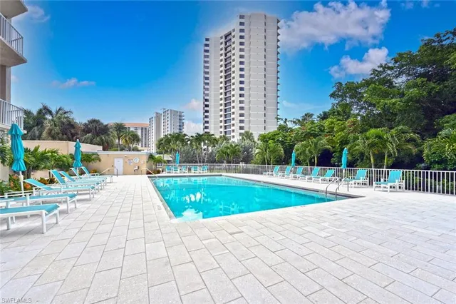 a view of a swimming pool with a lounge chair and palm trees