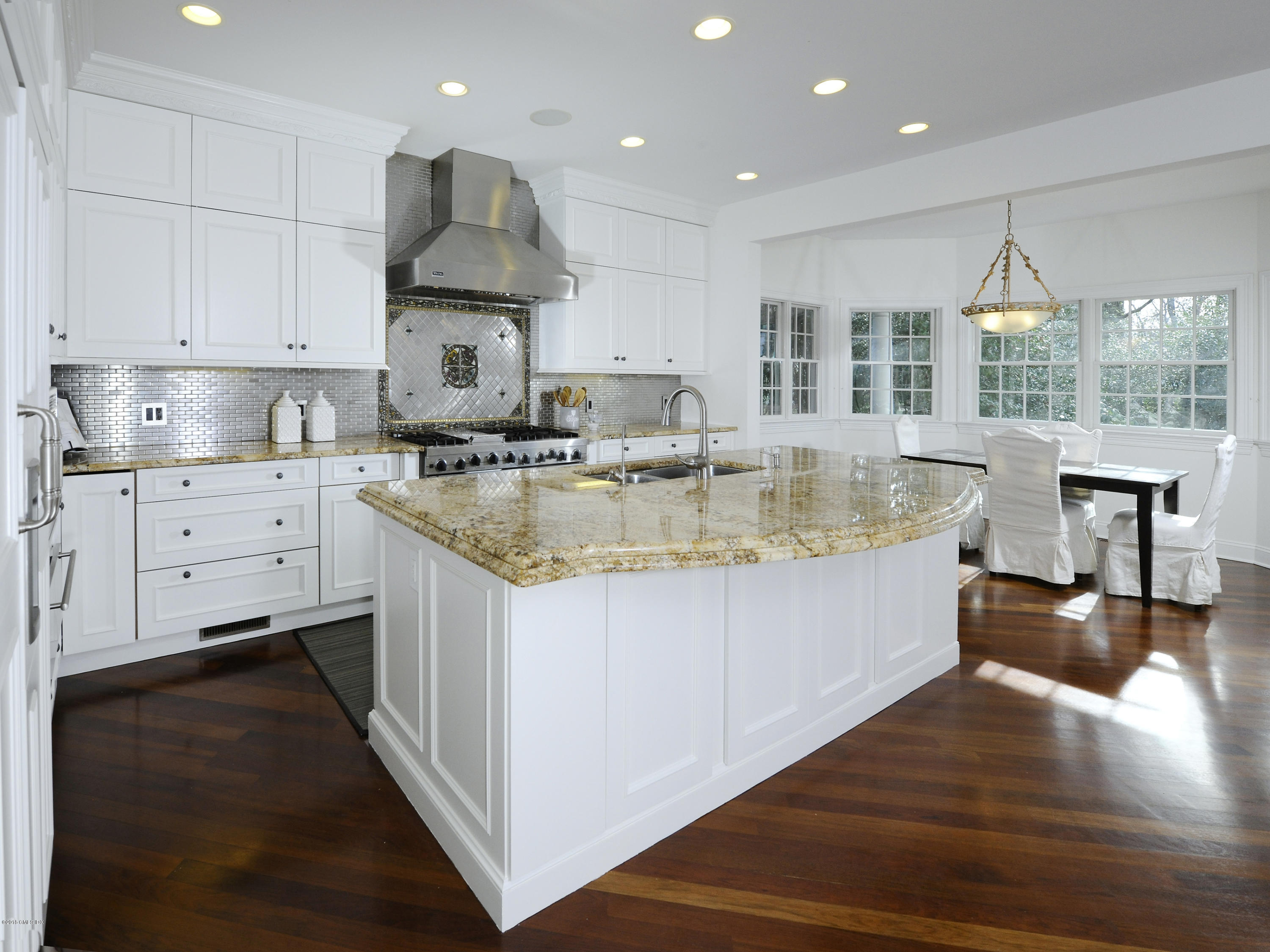 34 Hendrie Avenue Riverside, CT 06878 - Photo 6 of 28 a large kitchen with kitchen island a stove a sink a refrigerator and white cabinets with wooden floor