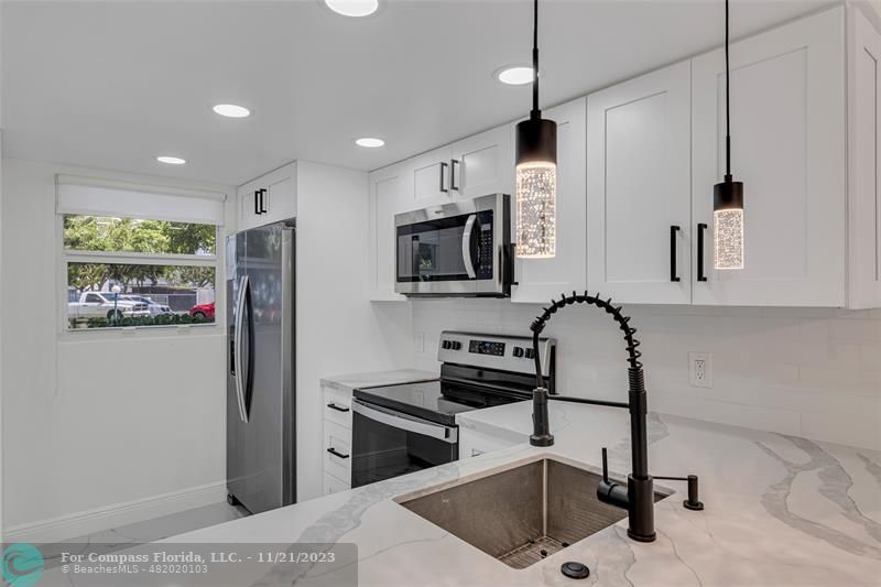 a kitchen with stainless steel appliances kitchen island granite countertop a sink and a refrigerator