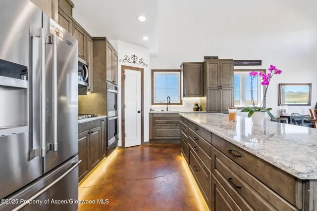 a kitchen with stainless steel appliances granite countertop a sink and a refrigerator