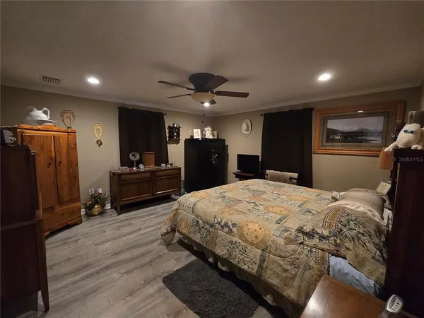 a large bedroom with a bed and a large kitchen space with wooden floor