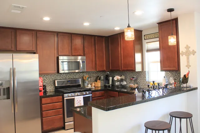 a kitchen with stainless steel appliances granite countertop wooden cabinets a refrigerator and a stove