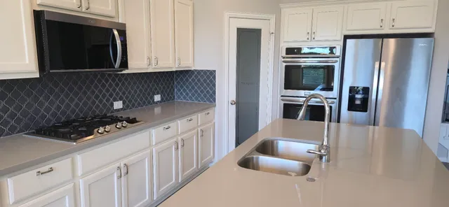 a kitchen with white cabinets and stainless steel appliances