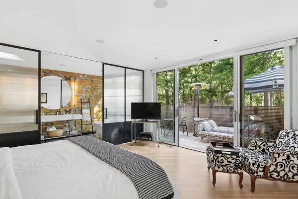 a bedroom with a bed a large window and a flat tv screen