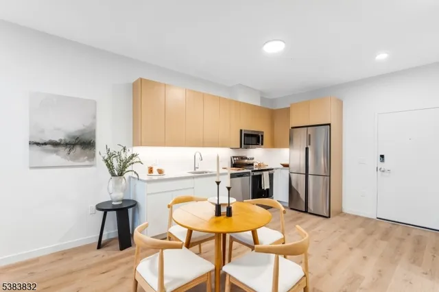 a kitchen with stainless steel appliances kitchen island granite countertop a refrigerator a stove a sink dishwasher a dining table and chairs with wooden floor