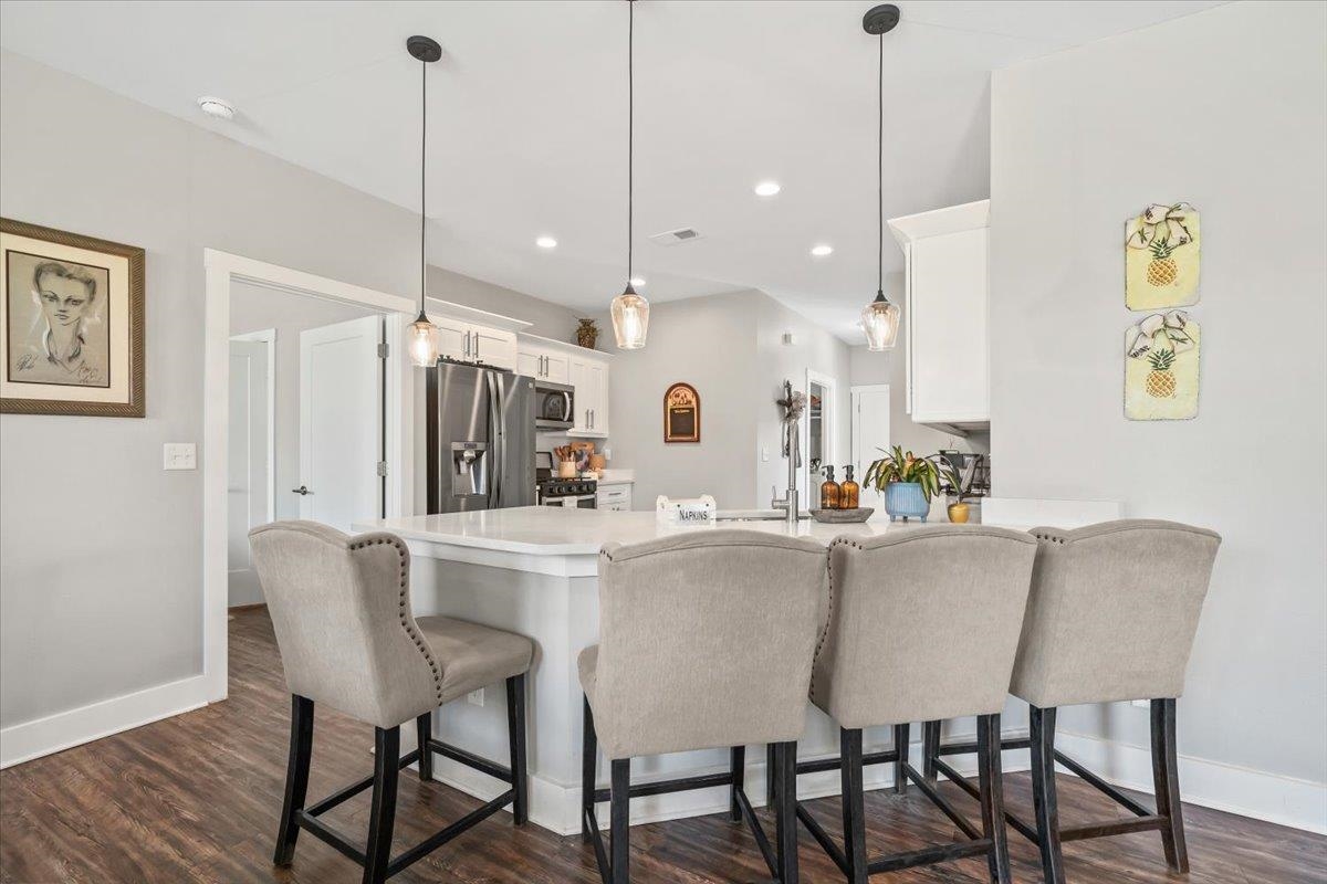 415 Abbey Road, Unit D Munford, TN 38058 - Photo 13 of 35 Open-concept kitchen featuring a white countertop island, pendant lighting, white cabinetry, stainless steel appliances, and wood-finish flooring