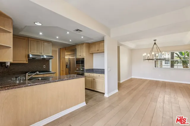 a large kitchen with kitchen island a large counter top stainless steel appliances and cabinets