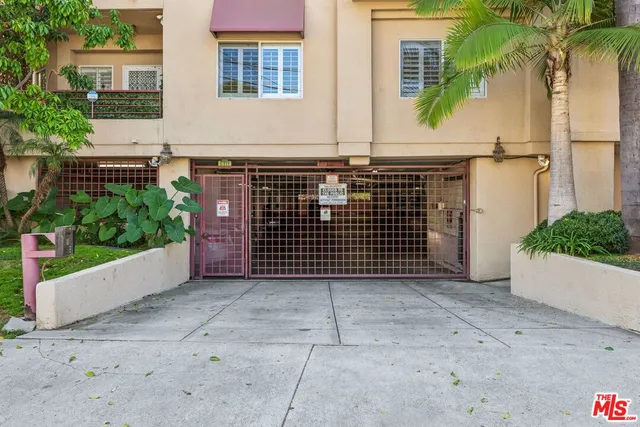 a view of a brick house with plants and wooden fence