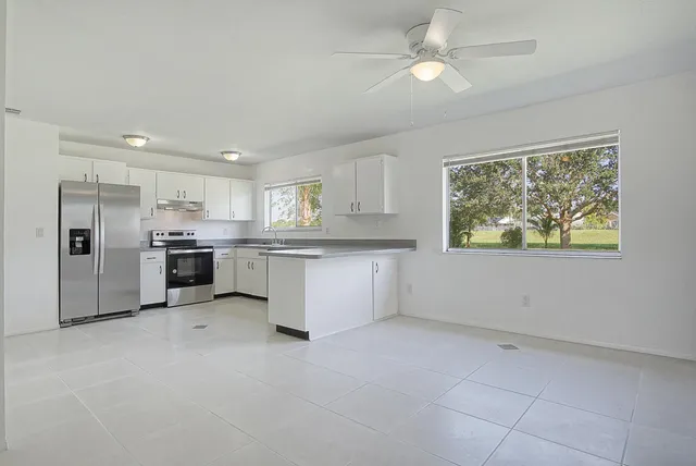 a view of kitchen with granite countertop cabinets and refrigerator
