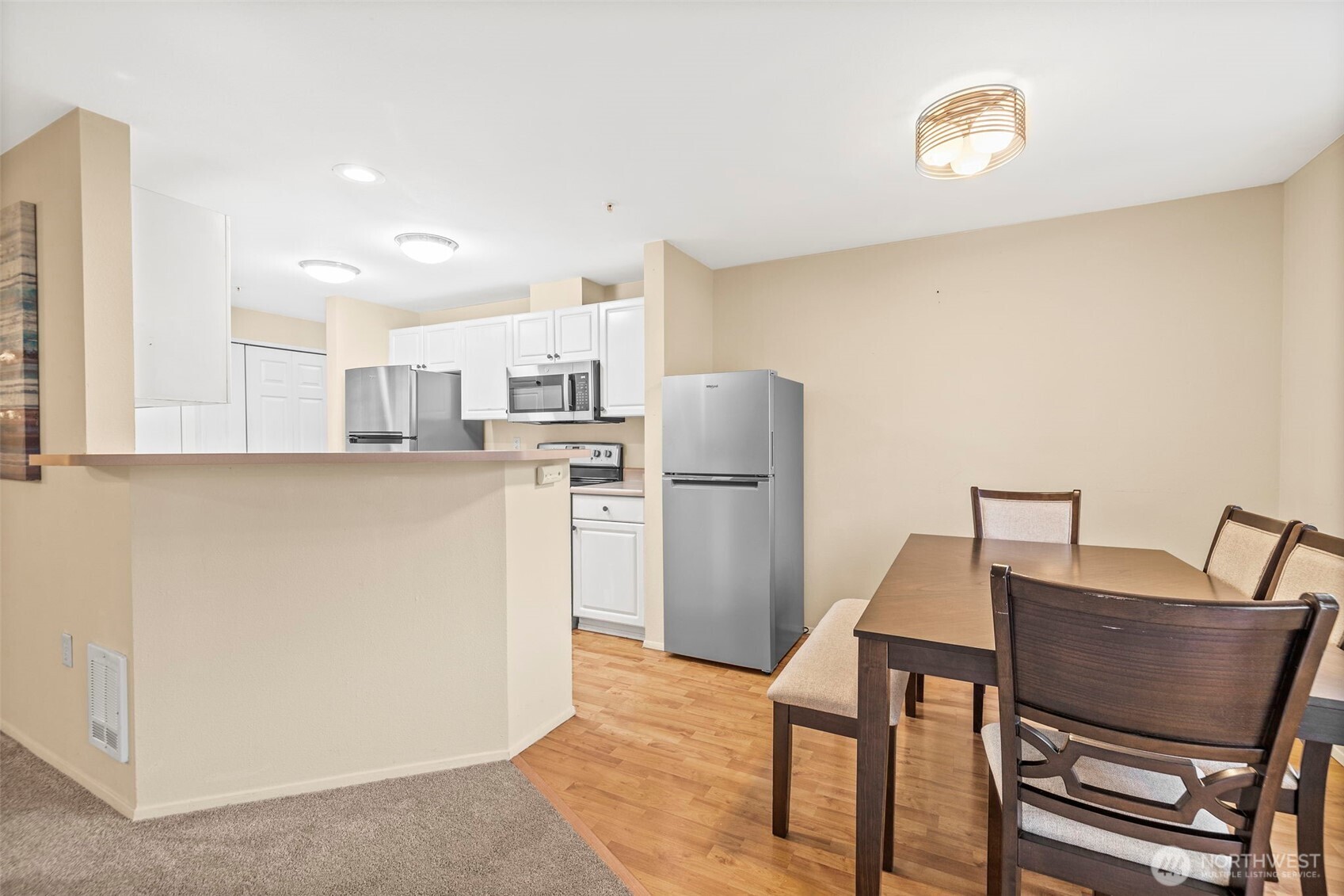 10824 Southeast 170th Street, Unit B103 Renton, WA 98055 - Photo 10 of 31 a kitchen with stainless steel appliances granite countertop a refrigerator a stove a sink a dining table and chairs