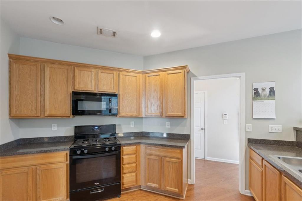 2747 High Creek Run Dacula, GA 30019 - Photo 14 of 48 a kitchen with stainless steel appliances granite countertop a stove a sink and a microwave