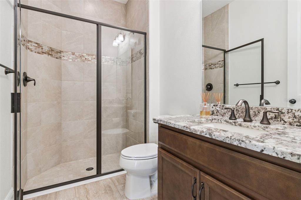 9009 Palm Key Avenue Oldsmar, FL 34677 - Photo 29 of 43 a bathroom with a granite countertop sink a toilet and shower