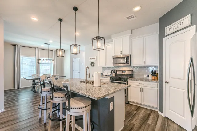 a kitchen with granite countertop a refrigerator a stove a kitchen island with a dining table and chairs