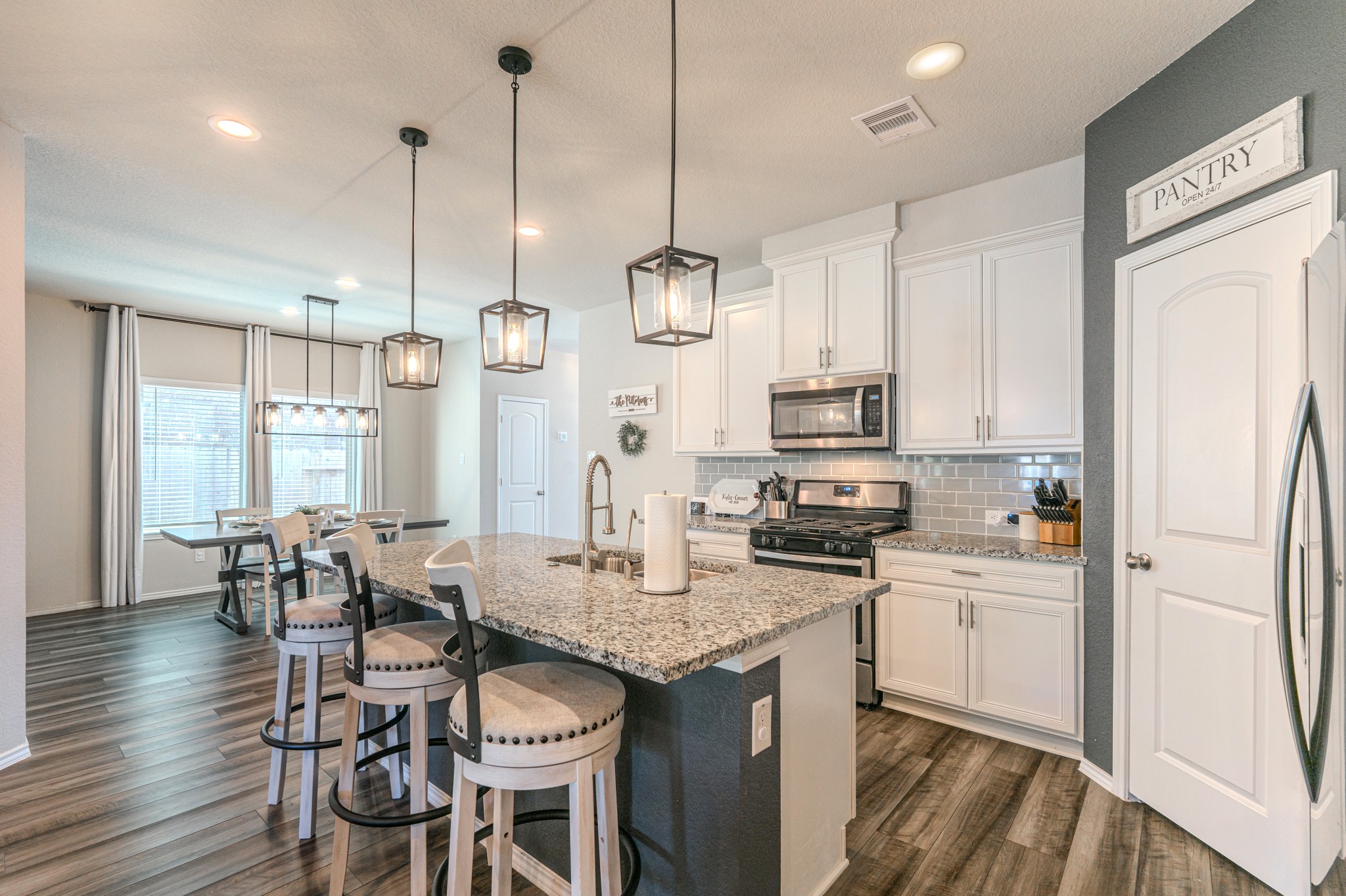 9221 Inland Leather Lane Conroe, TX 77385 - Photo 16 of 47 a kitchen with granite countertop a refrigerator a stove a kitchen island with a dining table and chairs