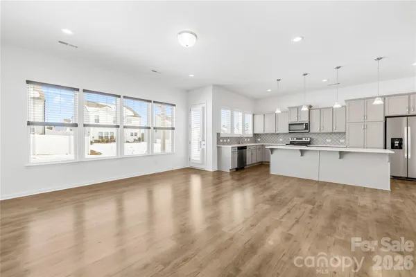 a large kitchen with stainless steel appliances granite countertop a large window a oven and a granite countertops with wooden floor