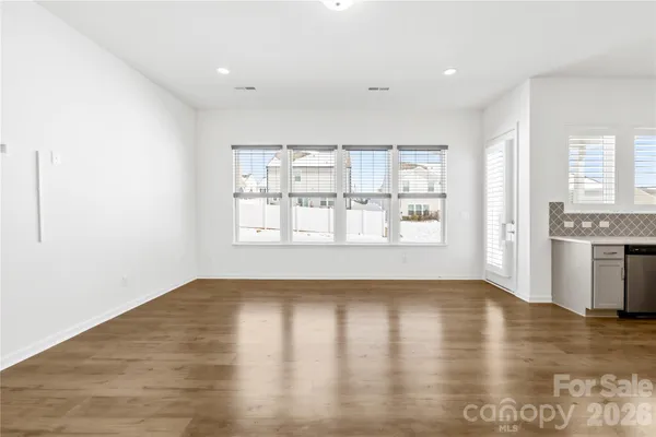 a view of an empty room with window and wooden floor