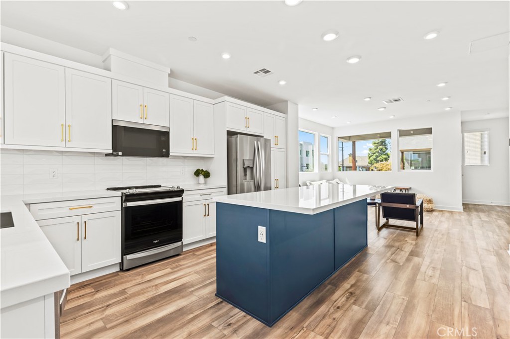609 South Lyon Street Santa Ana, CA 92705 - Photo 12 of 36 a kitchen with stainless steel appliances granite countertop a stove top oven a sink dishwasher and a refrigerator with wooden floor