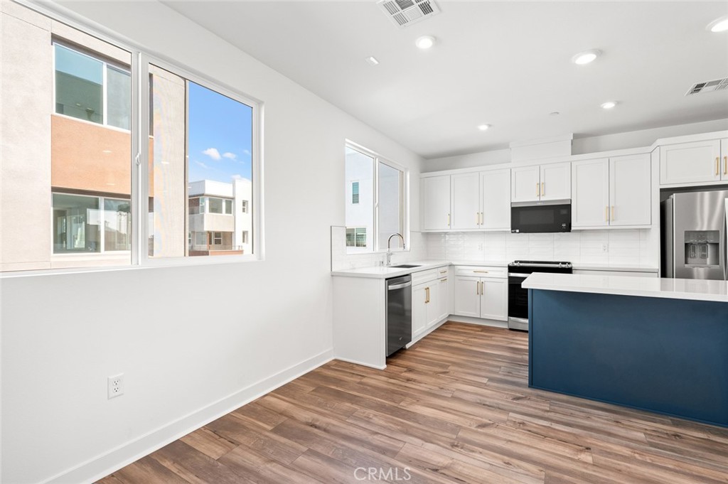 609 South Lyon Street Santa Ana, CA 92705 - Photo 14 of 36 a kitchen with granite countertop white cabinets and wooden floor