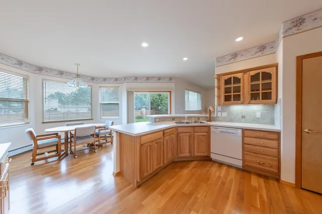 a kitchen with stainless steel appliances granite countertop wooden floors and white cabinets