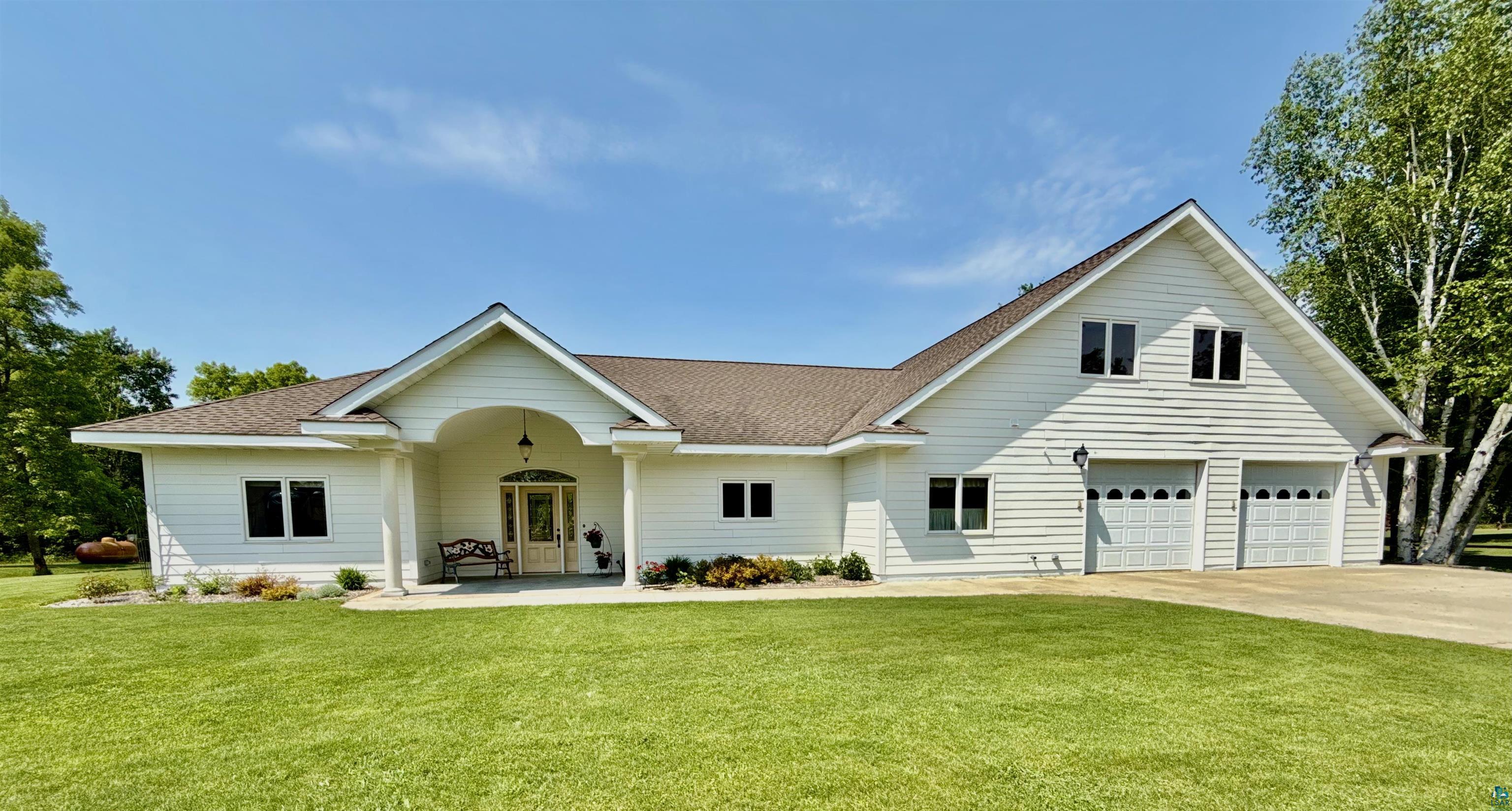 View of front of property with driveway, a front lawn, a shingled roof, and a garage